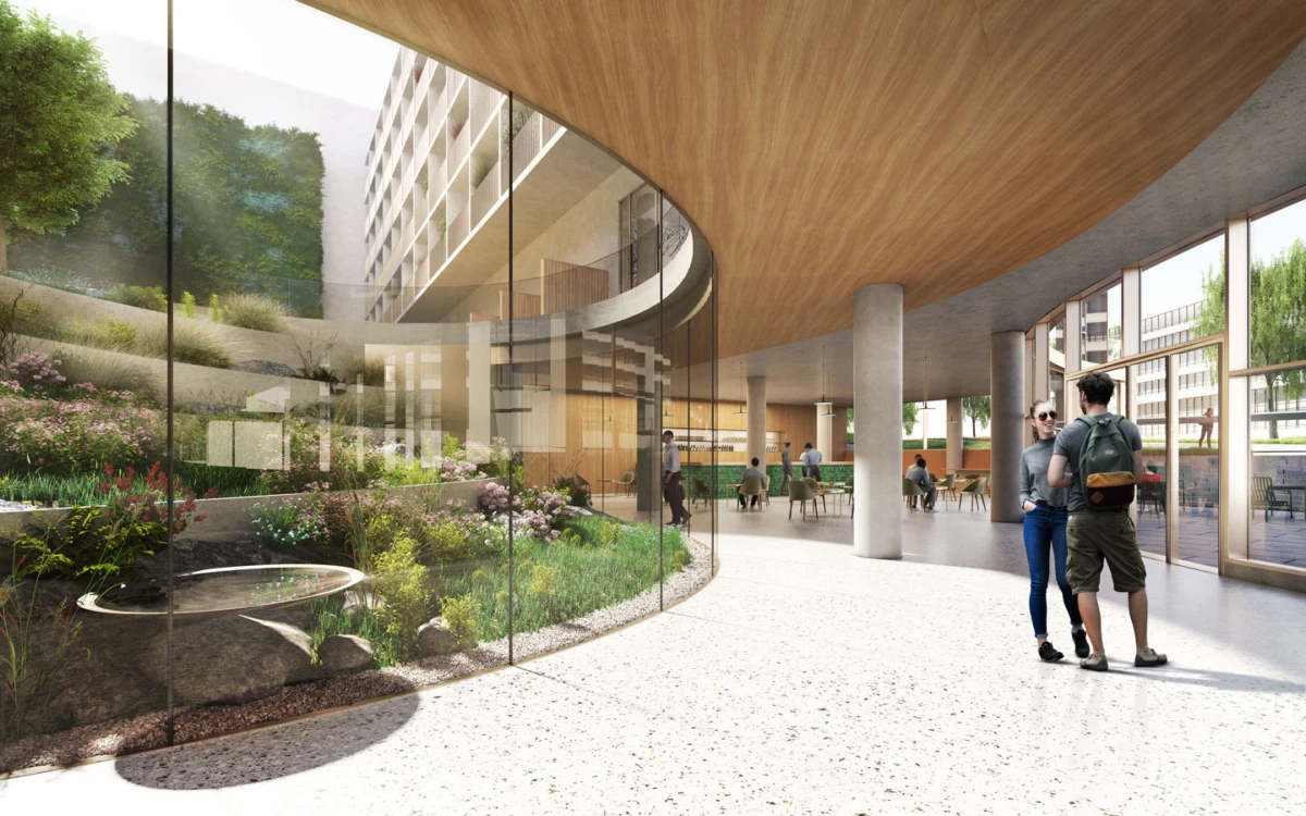 Two people converse in a modern glass-walled atrium with an indoor garden and curved wooden ceiling.