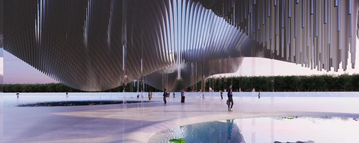 Curved canopy installation with hanging metallic fins over a shallow reflective pool; people walk across an open outdoor plaza at dusk.