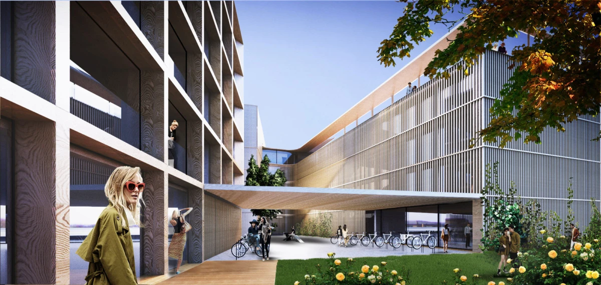Modern architectural complex with a central courtyard; pedestrians and cyclists walk through an open plaza beside bike racks and greenery.