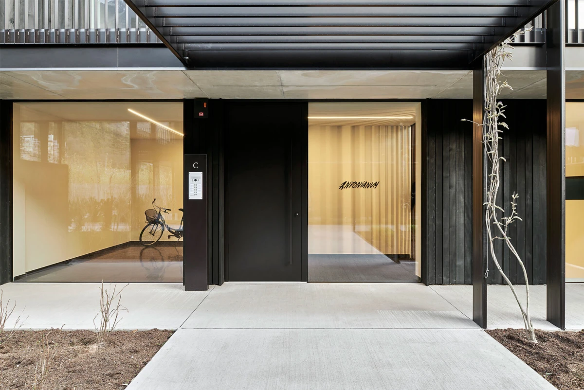 Modern storefront entrance with black door and glass facade; bicycle visible in left display window; beige-lit interior.