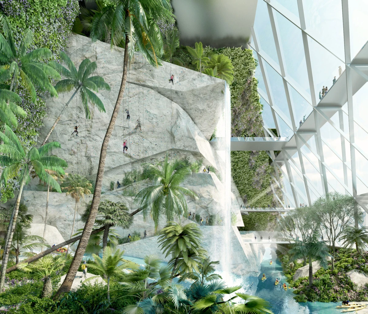 Indoor tropical atrium with artificial rock cliff and waterfall; climbers ascend the wall while visitors walk on glass bridges among palms and a pool.