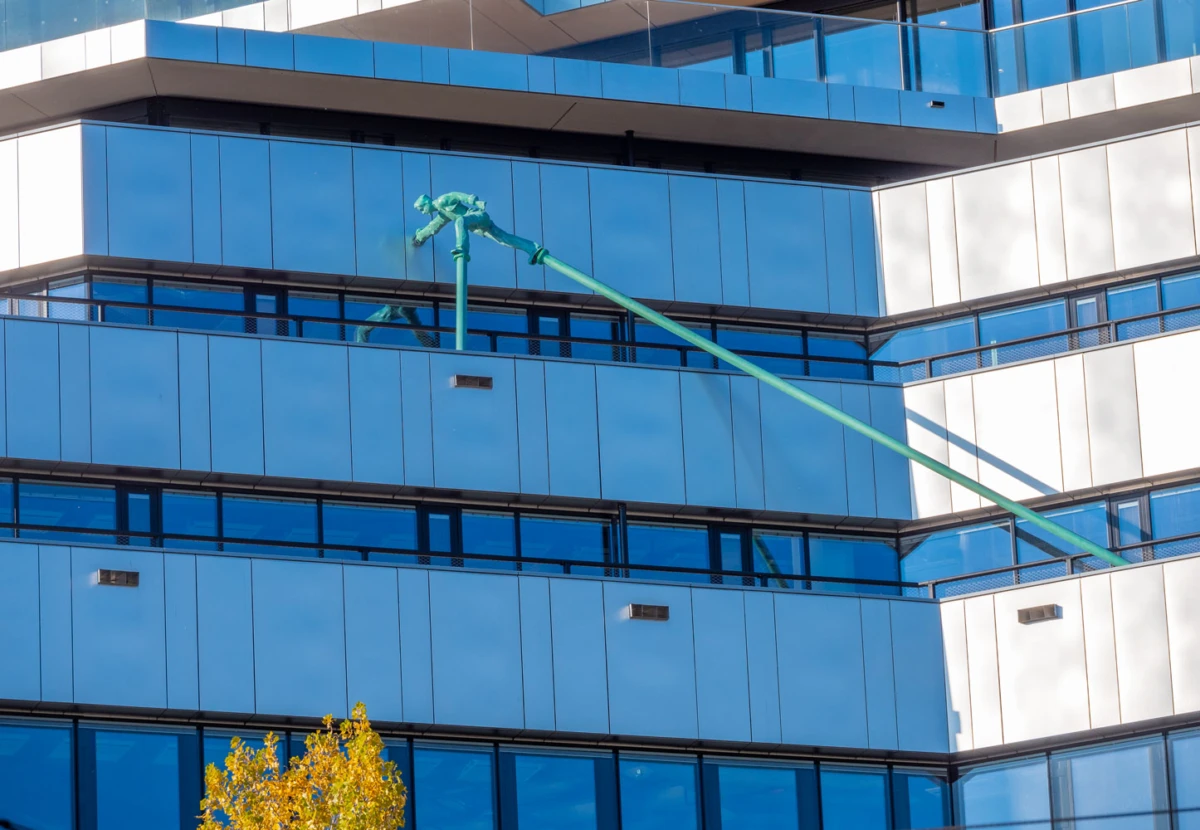 Green crane arm diagonally crosses a blue-glass office building.
