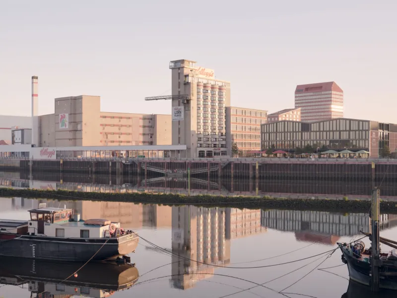 Urban riverfront with Kellogg's building, calm water reflecting the skyline, and moored boats in the foreground.