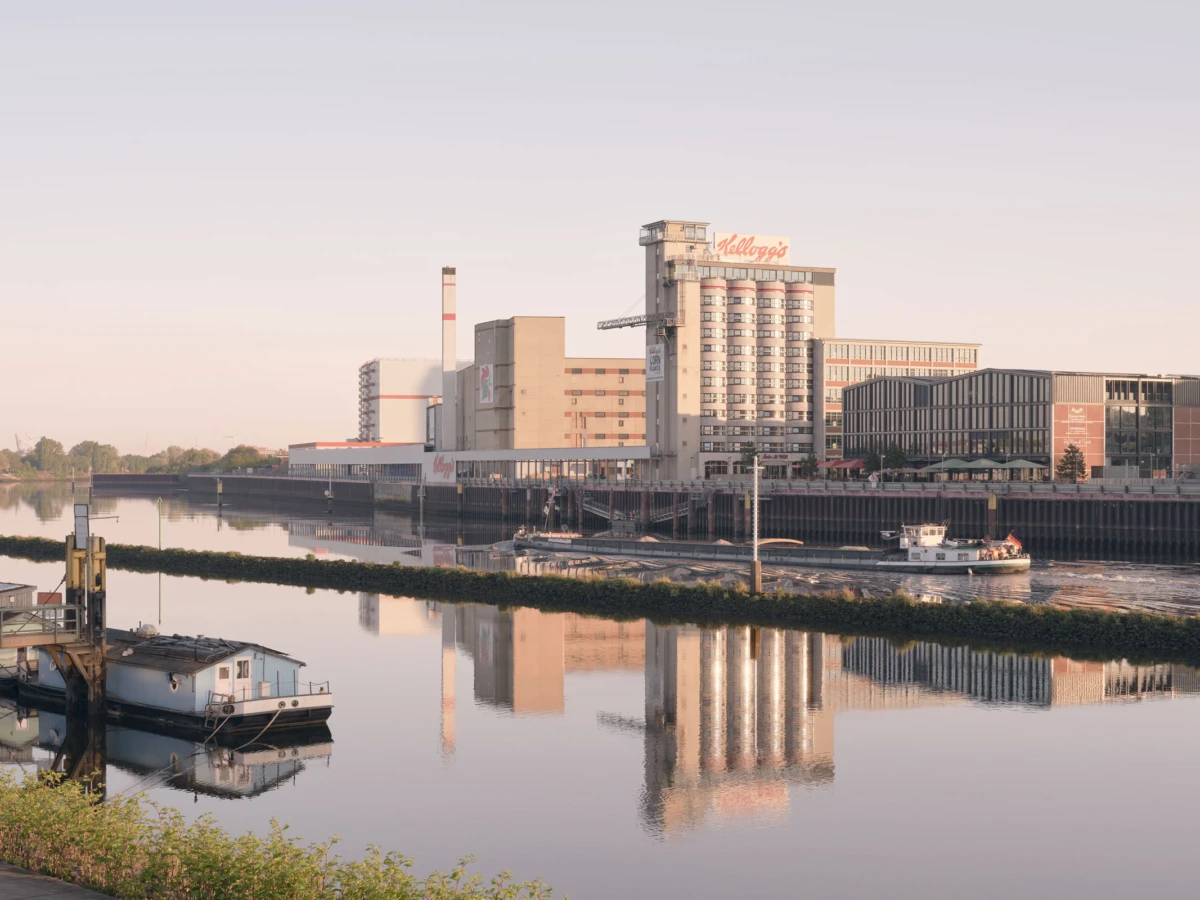 Kellogg's cereal factory on a riverside, small boat on calm water with reflections.