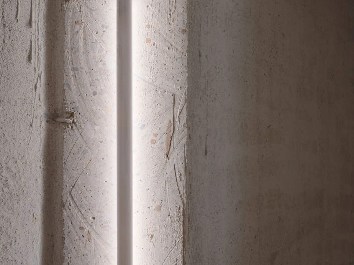 Concrete wall with a vertical glowing light strip; industrial interior.