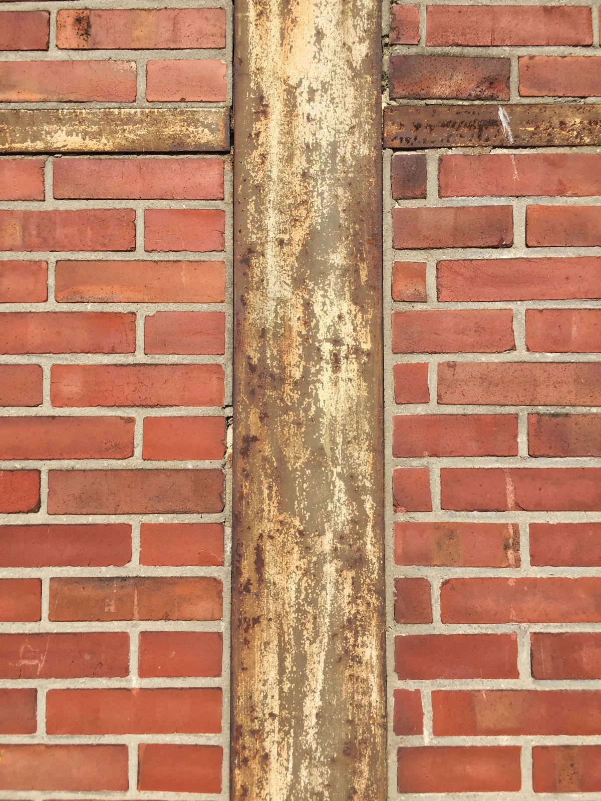 Central vertical rusted metal strip between red brick walls.