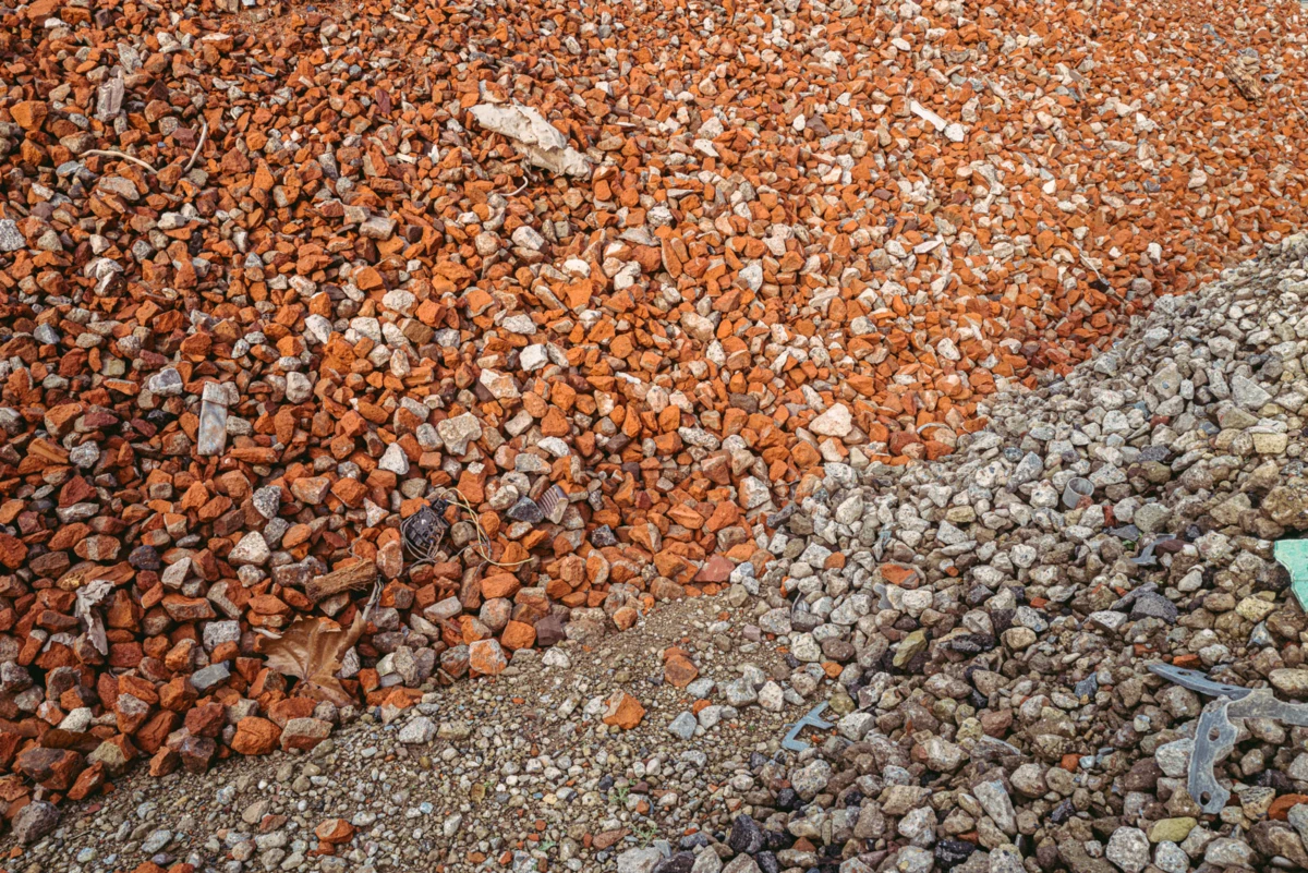 Orange-red gravel pile with gray rubble at a construction site
