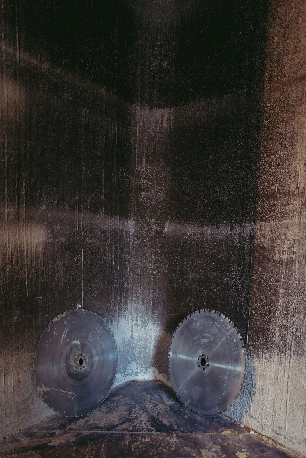 Two circular metal saw blades resting in a soot-blackened, charred furnace corner.