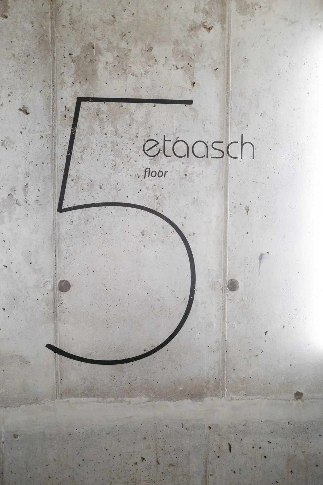 Large black numeral 5 painted on a concrete wall.