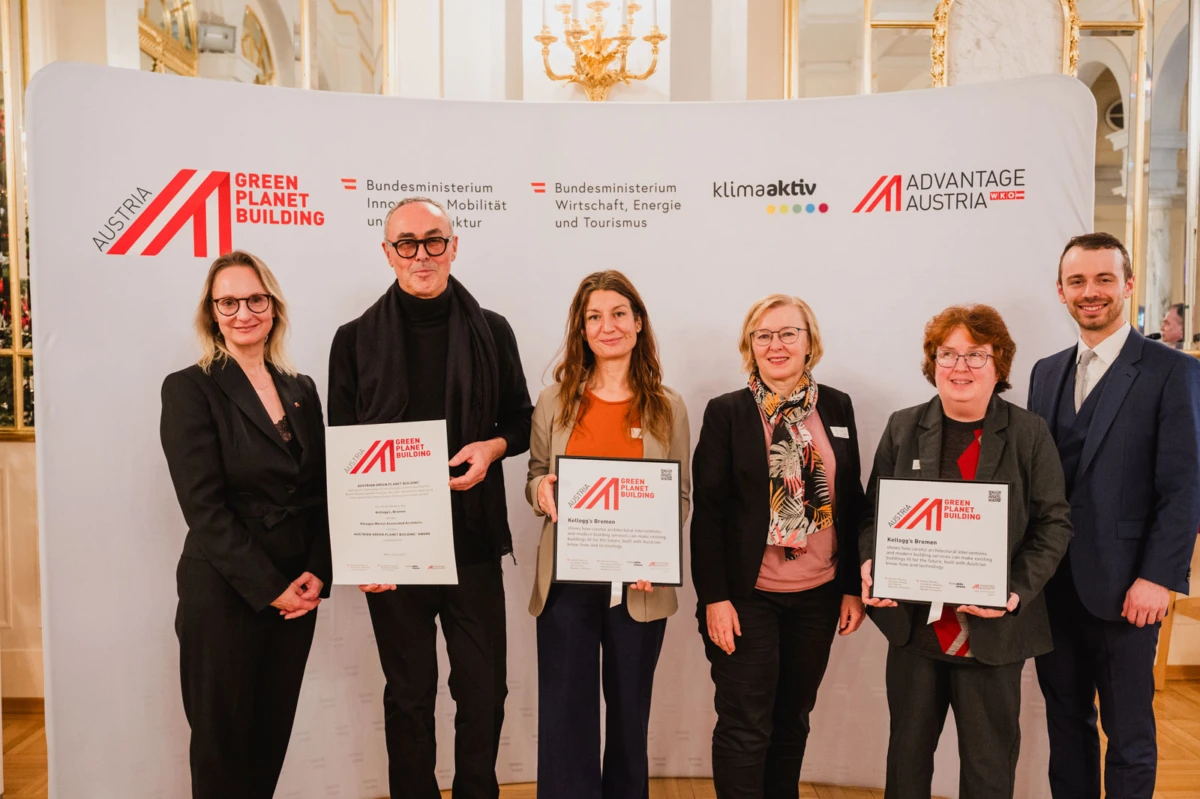 Six professionals stand in an ornate room, holding certificates in front of a branded backdrop.