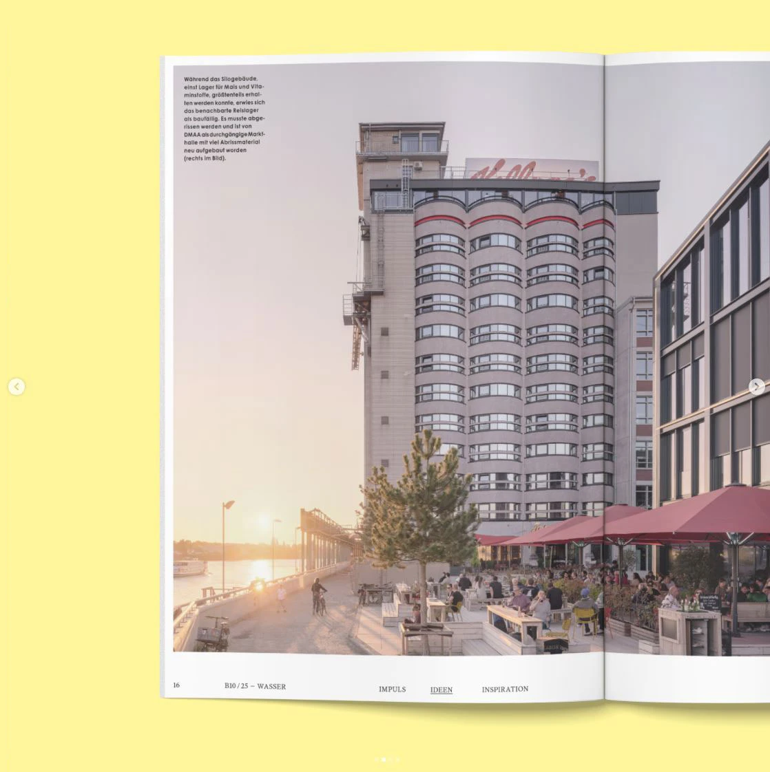 Tall cylindrical residential building with curved windows beside a waterfront promenade and outdoor cafe at sunset.