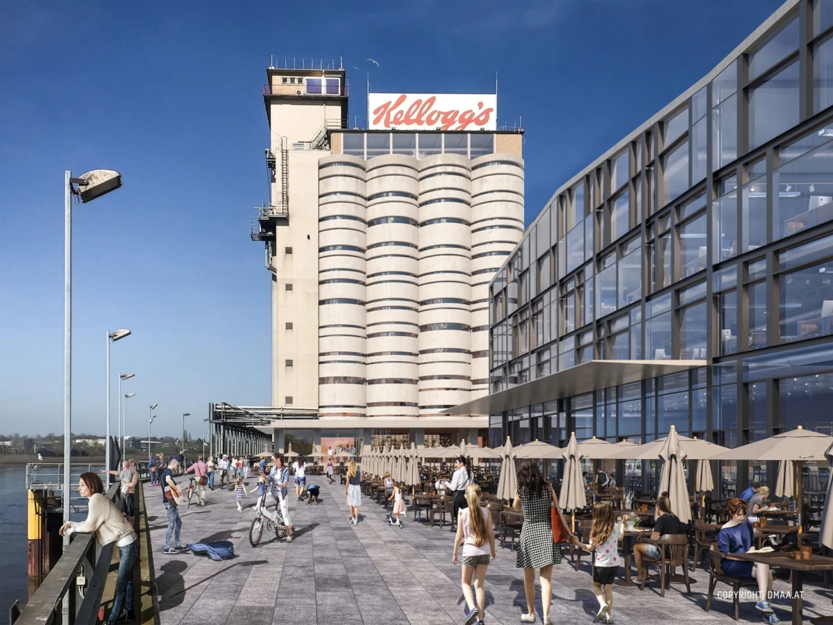 Kellogg's silo towers beside a glass-walled building; people stroll, cycle, and dine on the waterfront promenade.