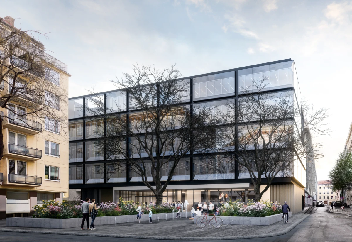 Modern glass-fronted office building with a dark steel frame, pedestrians and cyclists on a tree-lined urban street with flower planters.