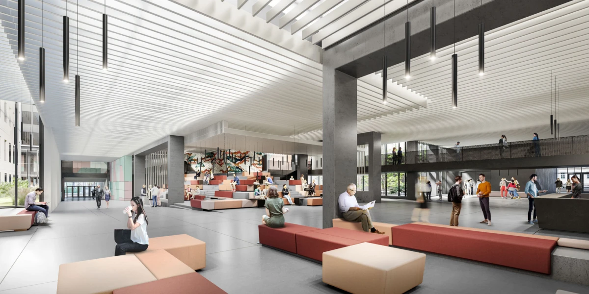 Open, modern atrium with colorful modular seating; people sit, walk, and chat under hanging pendant lights near a mezzanine.