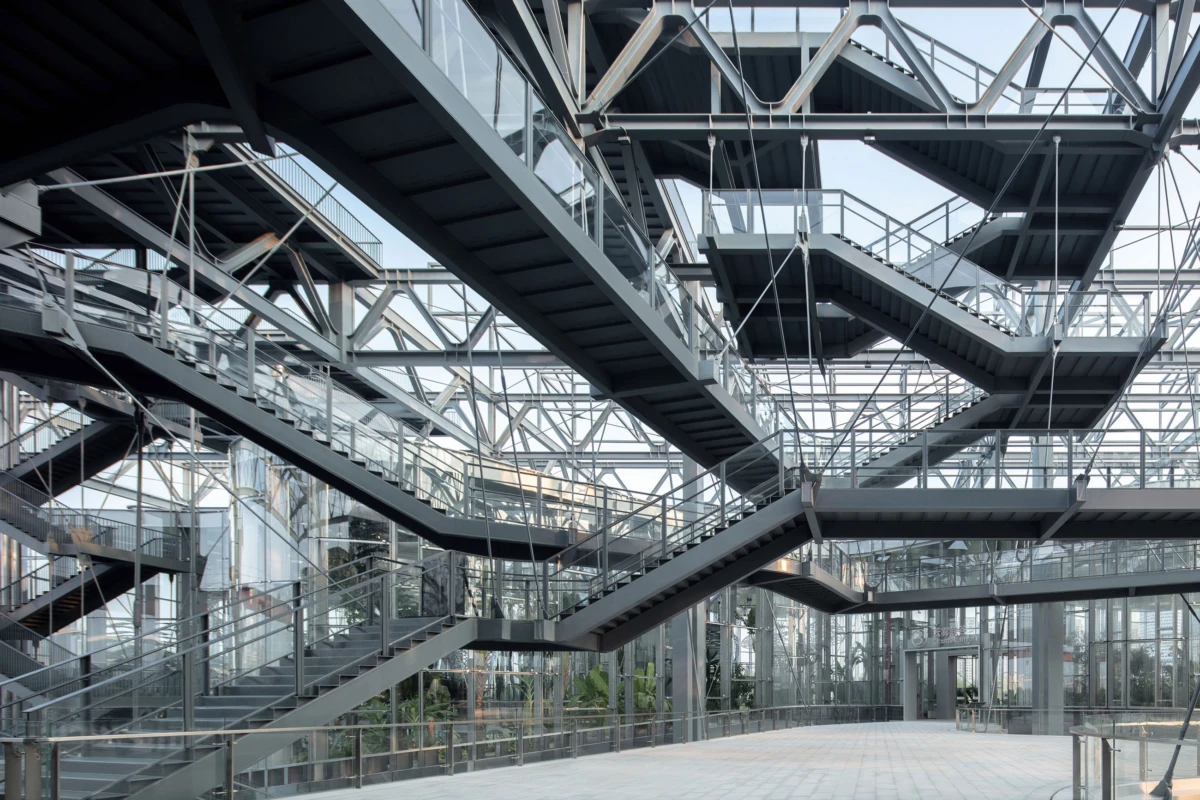 Crisscrossing steel staircases and glass railings weave through a modern architectural atrium.