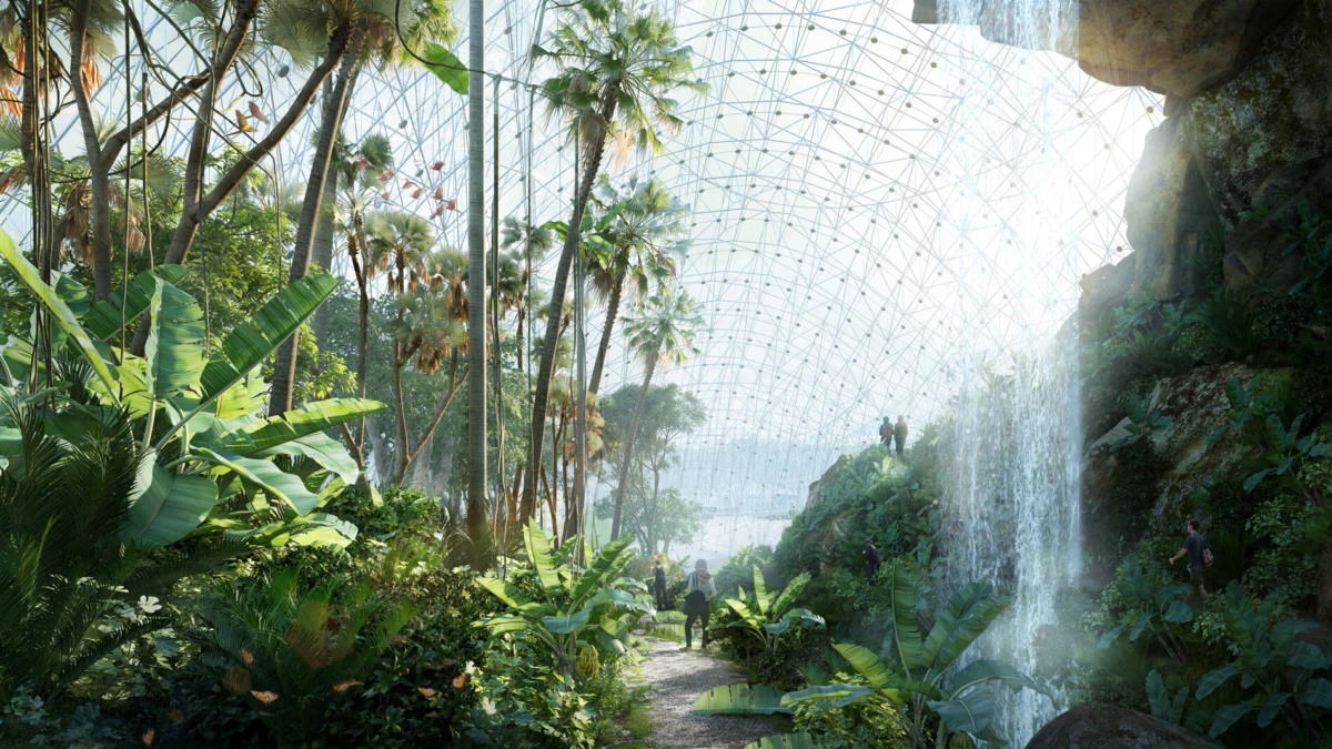 Visitors walk through an indoor tropical rainforest beneath a geodesic glass dome beside a waterfall.