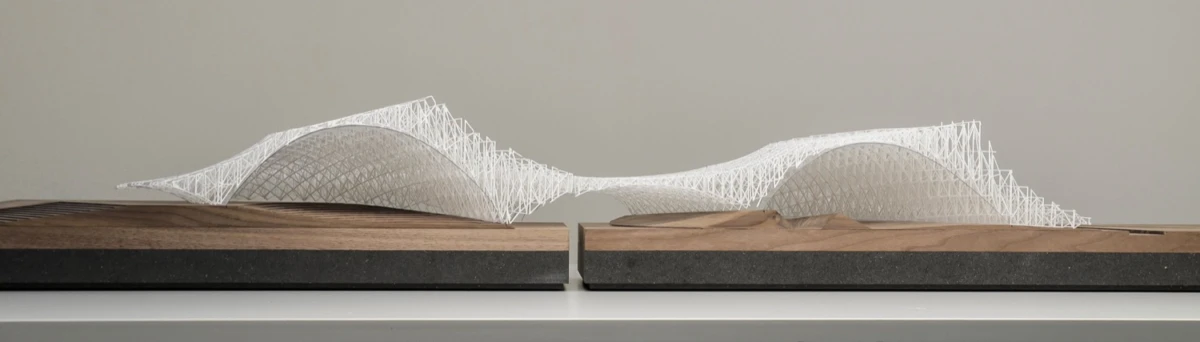 Two white lattice wave sculptures mounted on wooden bases, displayed on a shelf against a gray wall.