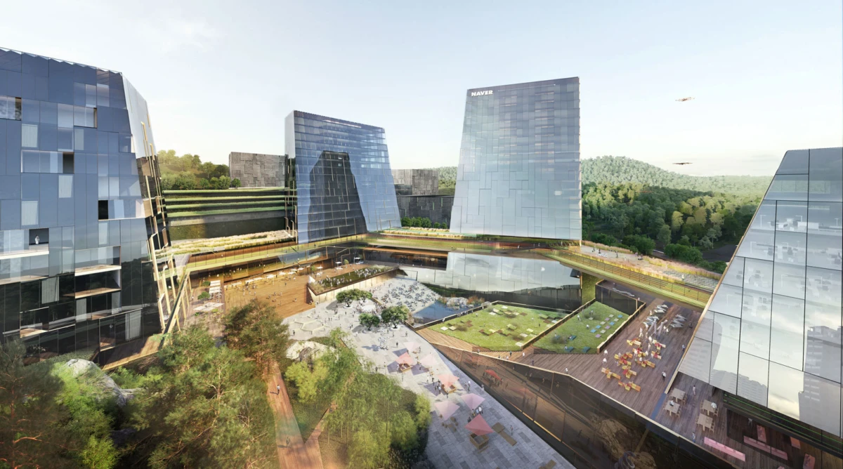 Aerial view of a glass-clad office campus with interconnected towers around a central courtyard and green terraces.