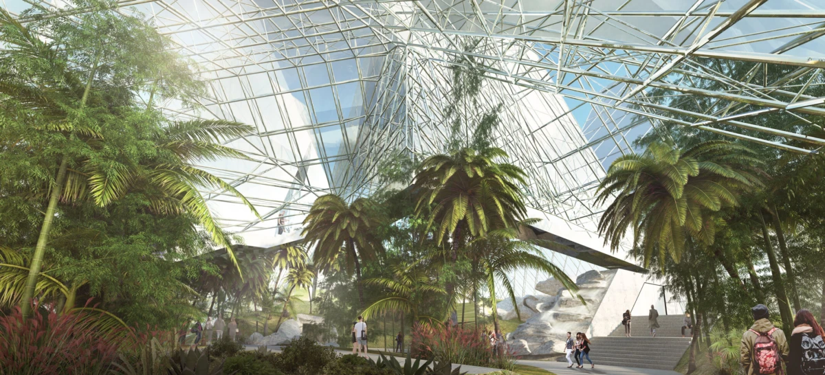 Indoor tropical conservatory with a glass and steel dome, lush palm trees, and visitors strolling along a landscaped path.