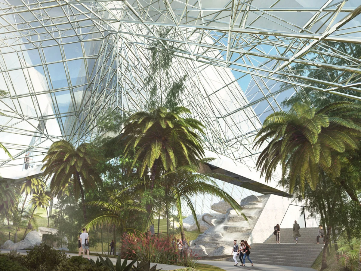 Glass-domed conservatory atrium with tropical palm trees, metal lattice roof, and stone stairs; visitors walk along a path.