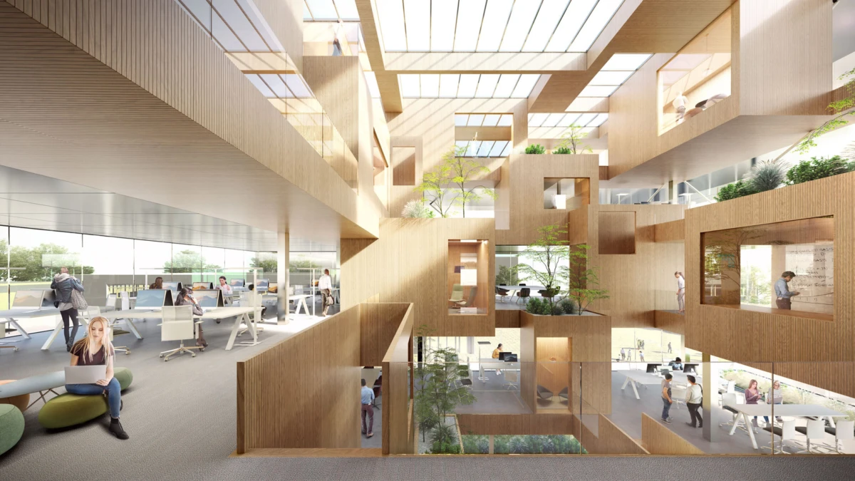 Open-plan workspace with a multi-level wooden cubic sculpture; people work at desks and lounges beside glass walls and greenery.