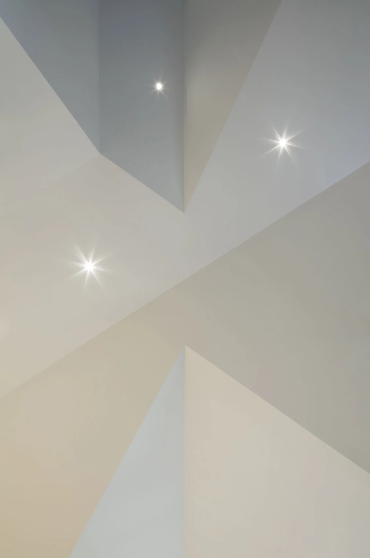 Geometric ceiling with intersecting gray and white triangles and several recessed starburst lights.