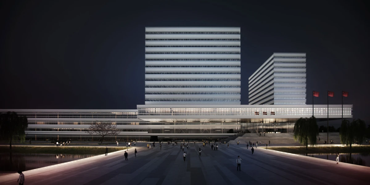 Nighttime view of a modern glass-and-steel office complex featuring two tall towers and a low-rise podium; pedestrians walk across a lit plaza.
