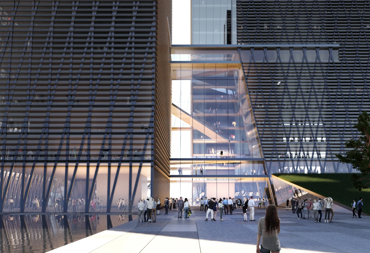 Crowd outside a modern glass-clad building with a central glass atrium; two diagonal lattice facades frame the entrance.