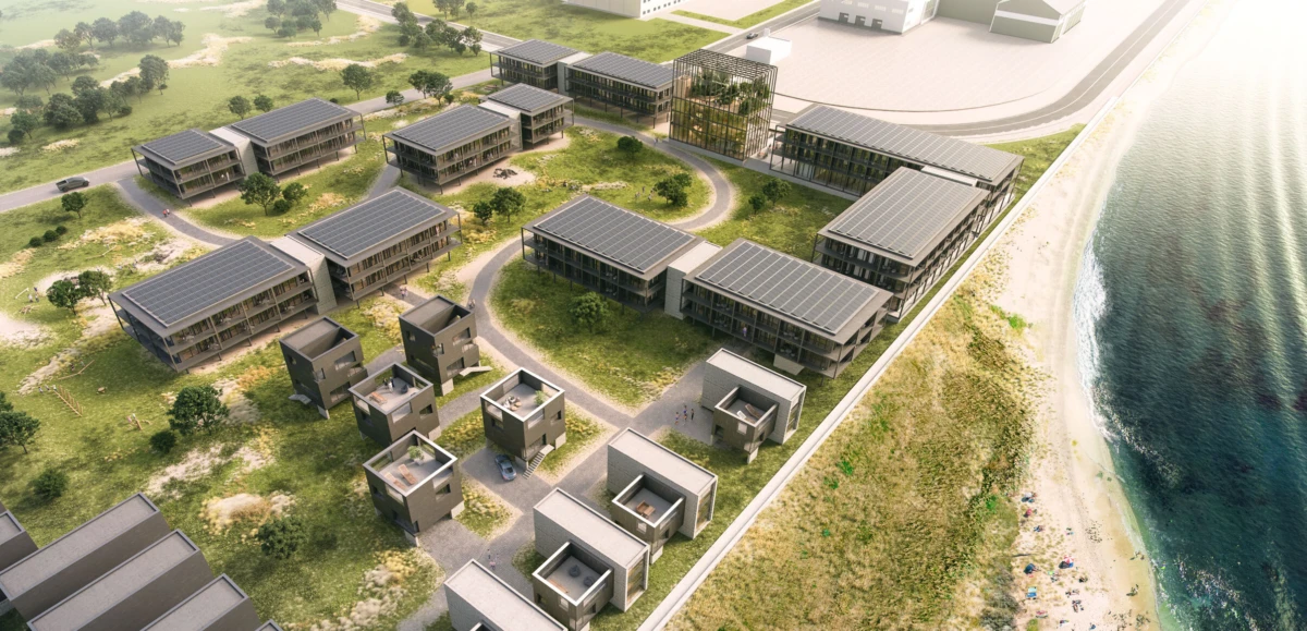 Aerial view of a beachfront residential campus with low-rise rectangular buildings, rooftop solar panels, and curved roads.