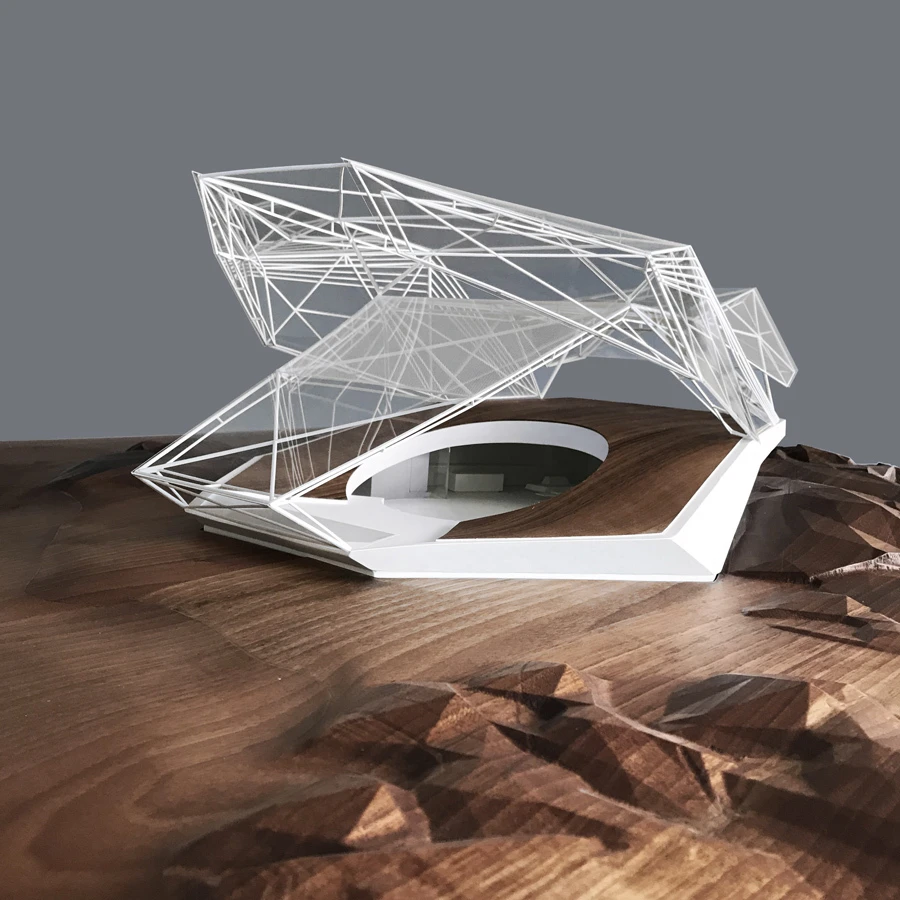 Futuristic glass-and-wireframe architectural pavilion model on a wooden terrain diorama.