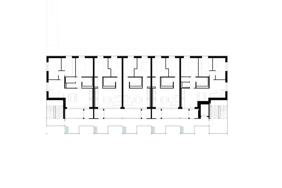 Architectural floor plan of a long rectangular building with a central corridor flanked by multiple rooms; stairs at both ends.