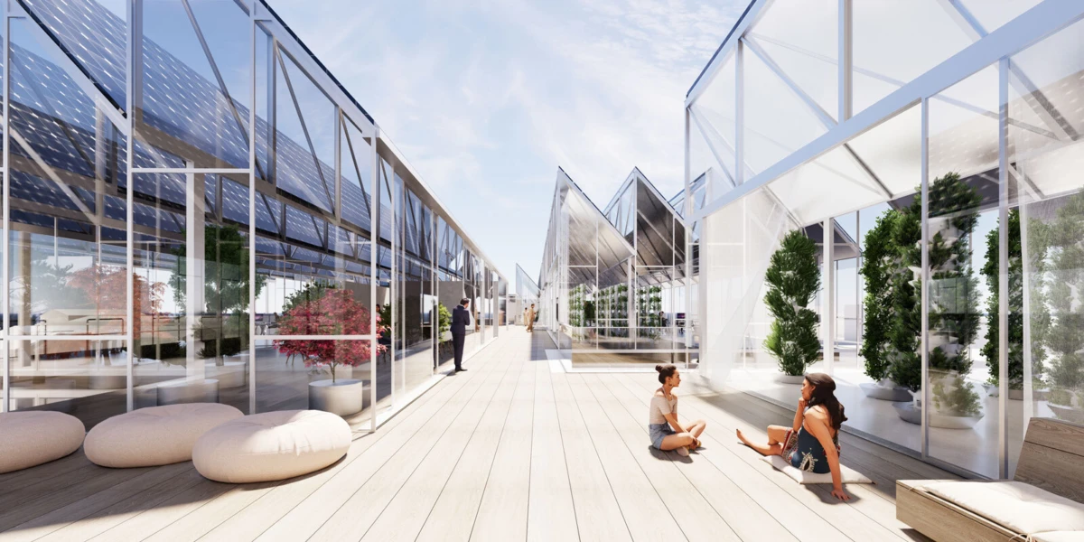 Two people sit on a wooden deck in a glass atrium, chatting amid potted trees.
