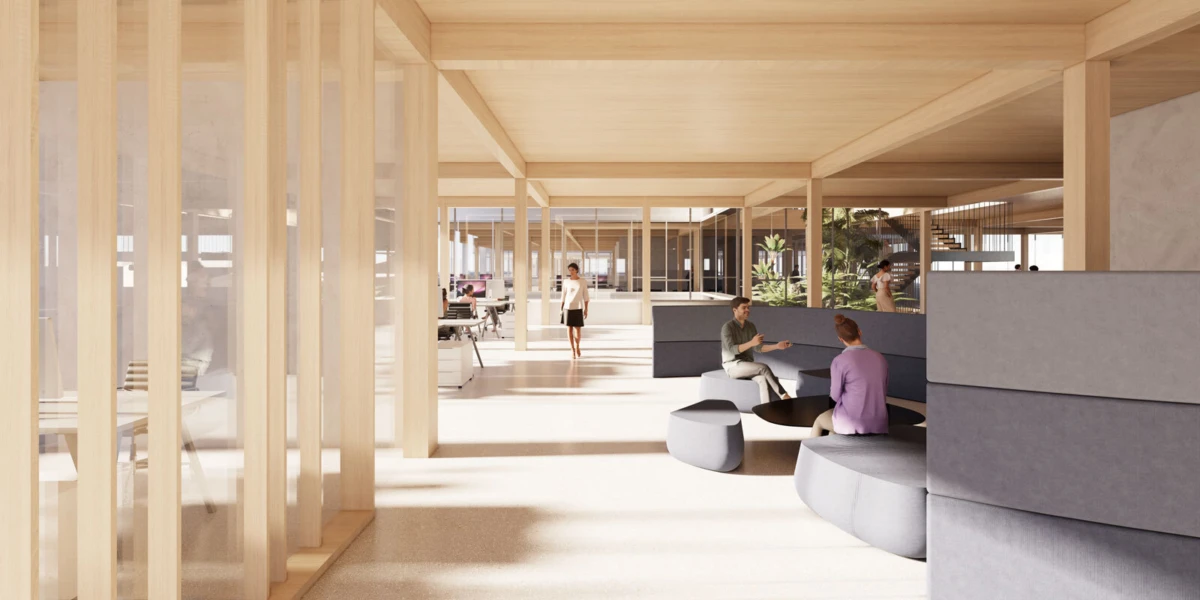 Colleagues converse in an open-plan, wood-columned office with circular gray sofas in a bright, sunlit space.