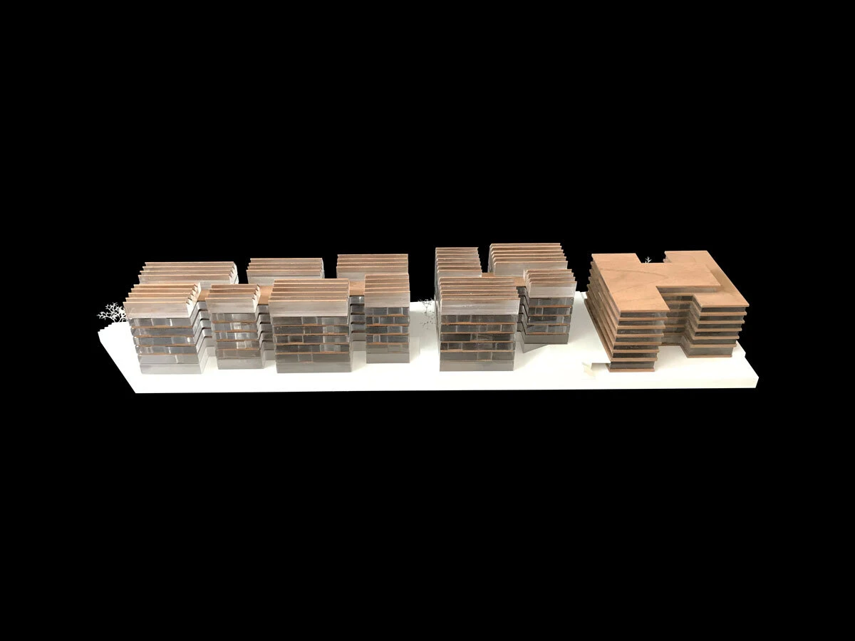 Architectural scale model of a city block with brown-topped residential blocks and an L-shaped building on a white display base.