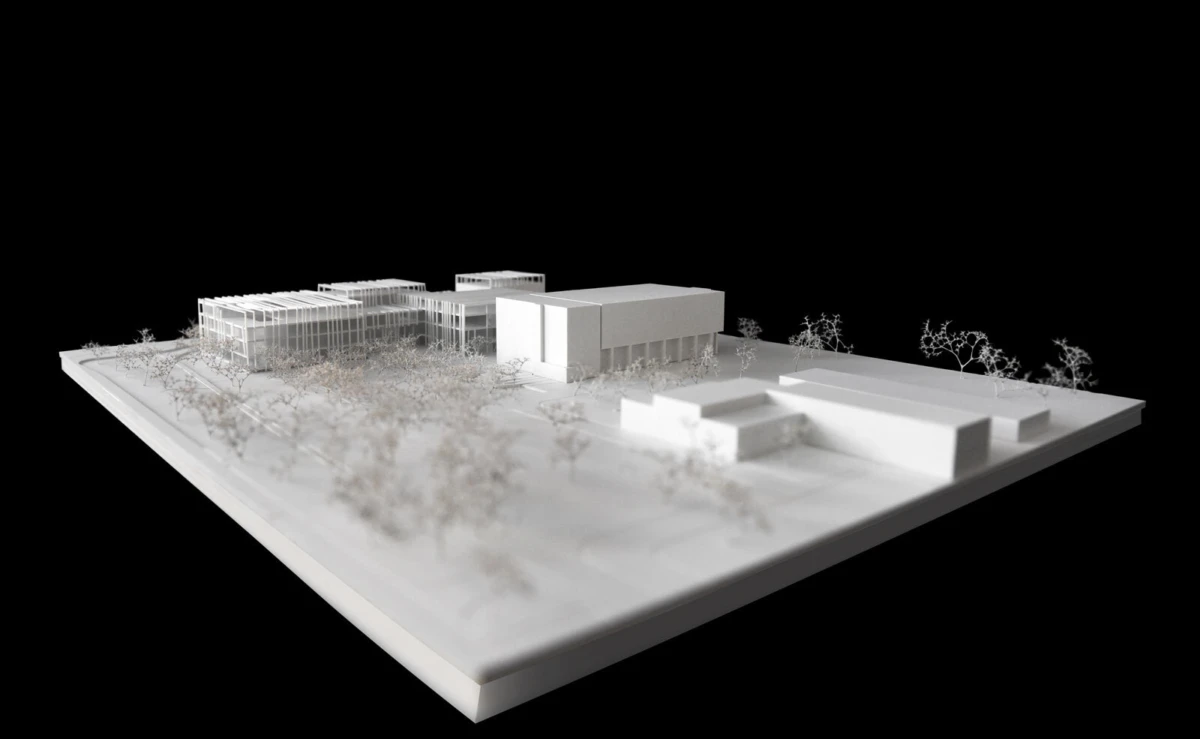 Architectural scale model of a modern building complex with glass-fronted blocks and surrounding trees on a white base.