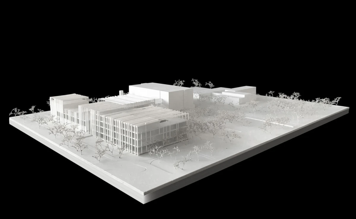 White architectural scale model of a modern multi-building campus on a raised base with trees.