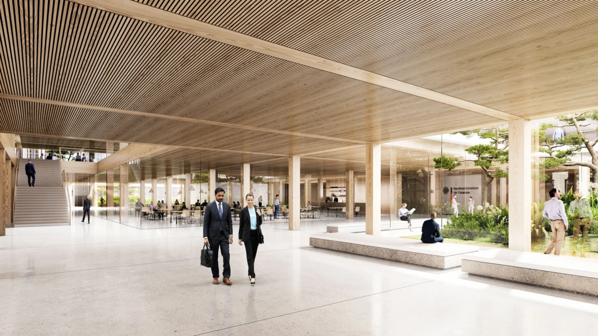 Two businesspeople walk side by side through a spacious atrium with a wood slat ceiling and glass walls; garden area on the right.