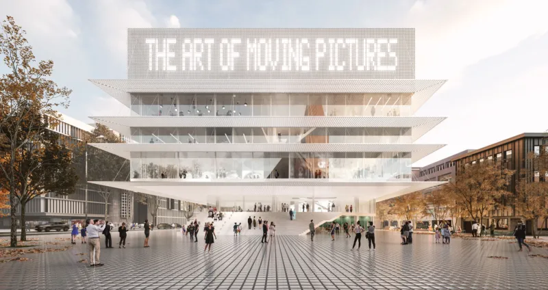 Modern glass museum with stacked cantilevered floors; people walk on a wide front plaza; sign reading 'THE ART OF MOVING PICTURES' atop.