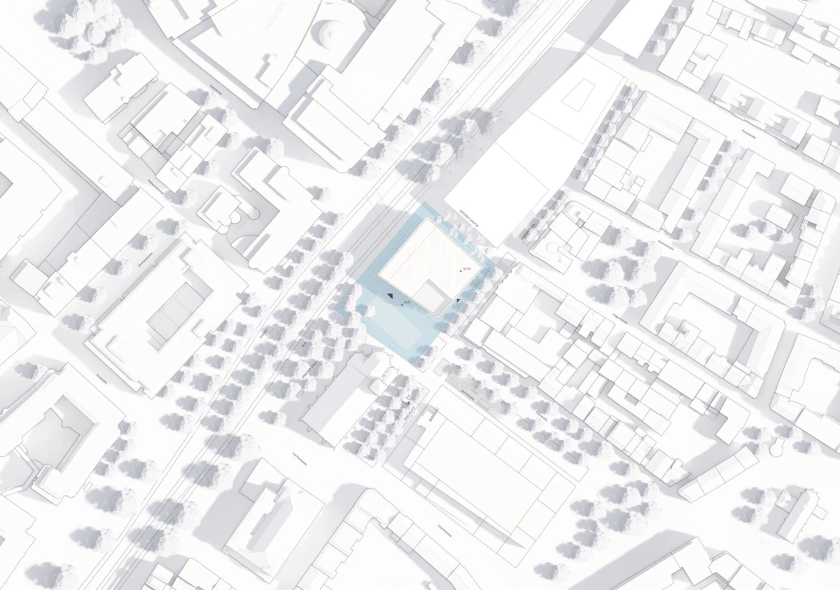 Aerial view of an urban block; central rectangular building is outlined in blue, with surrounding streets, blocks, and trees.