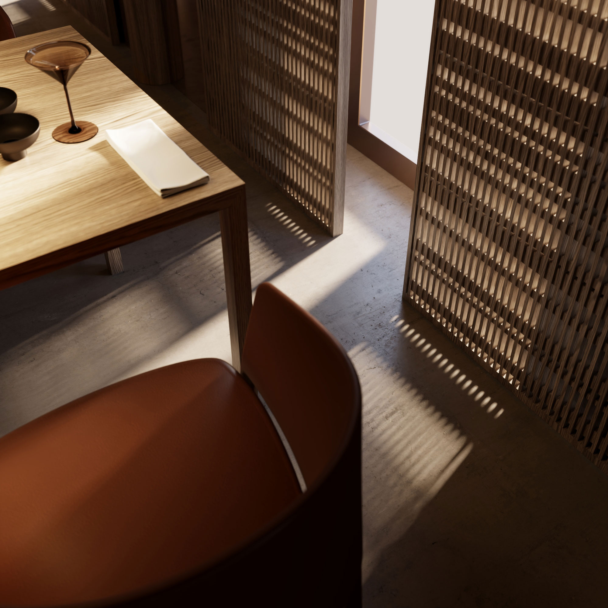 Wooden dining table with folded napkin and cocktail glass; woven lattice partition casts striped shadows, brown leather chair in foreground.