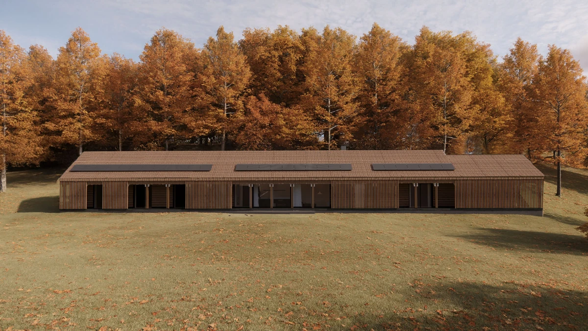 Long single-story wooden building with slatted walls and solar panels on the roof, standing in an autumnal grove of orange trees.