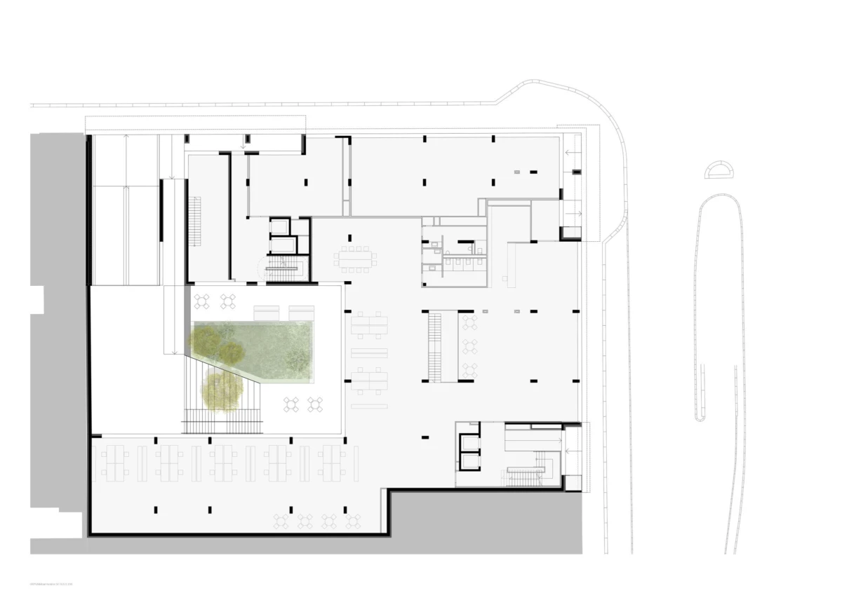 Architectural floor plan of a building with a central courtyard garden, multiple rooms, open workspaces, and an exterior curved driveway.