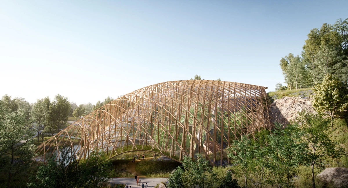 Timber lattice arch bridge over a stream in a lush forest; people walk beneath.