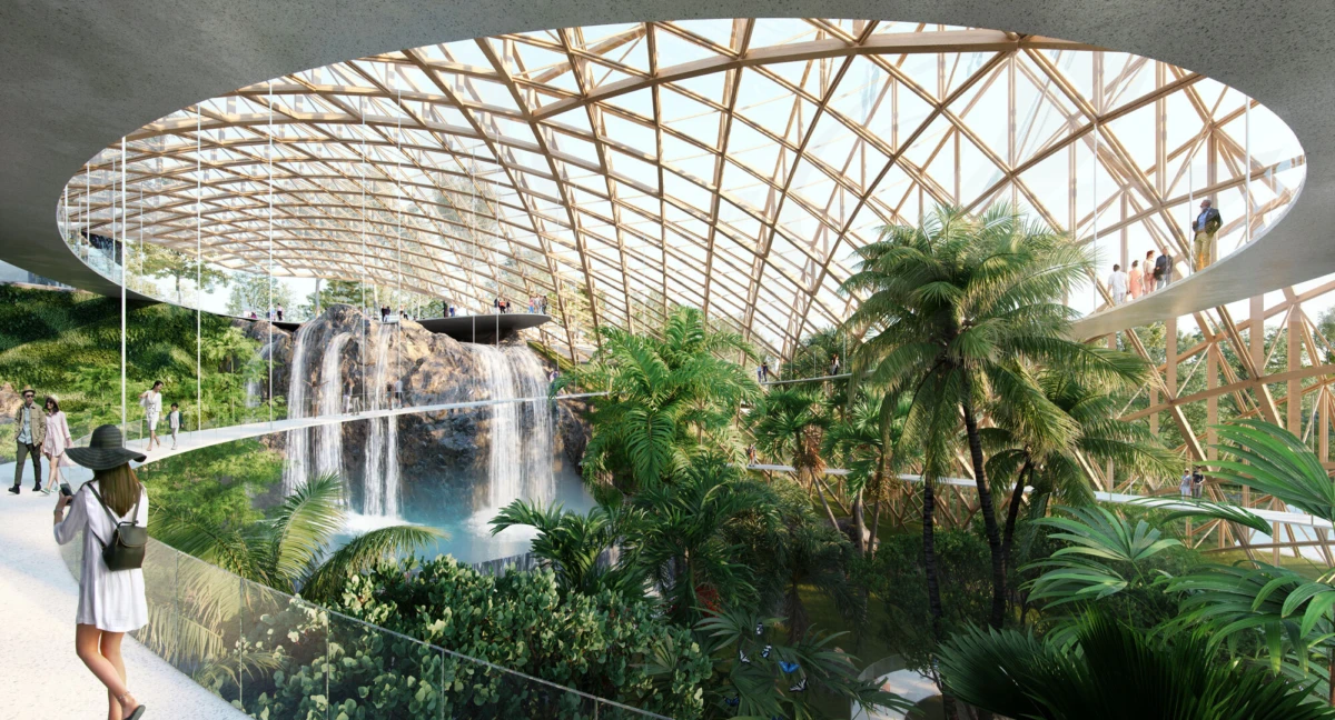 Indoor tropical conservatory under a glass lattice dome, with a waterfall and lush plants as visitors stroll along elevated walkways.