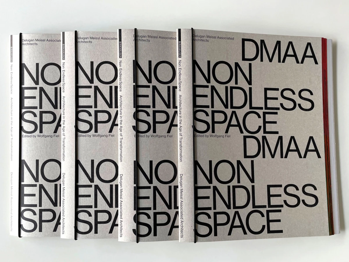 Row of four gray design books with bold NON ENDLESS SPACE typography; rightmost cover features DMAA.