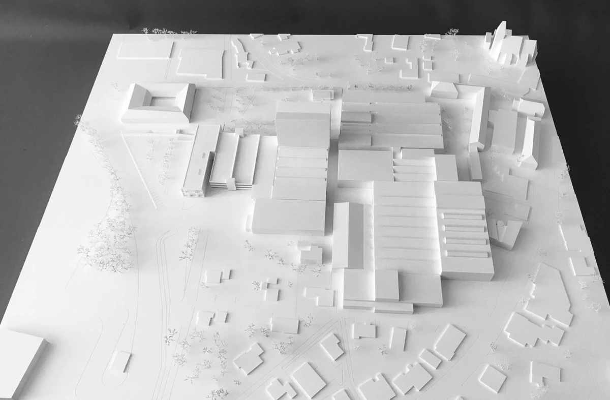 White architectural scale model of a large modern building complex on a site plan, displayed on a tabletop.