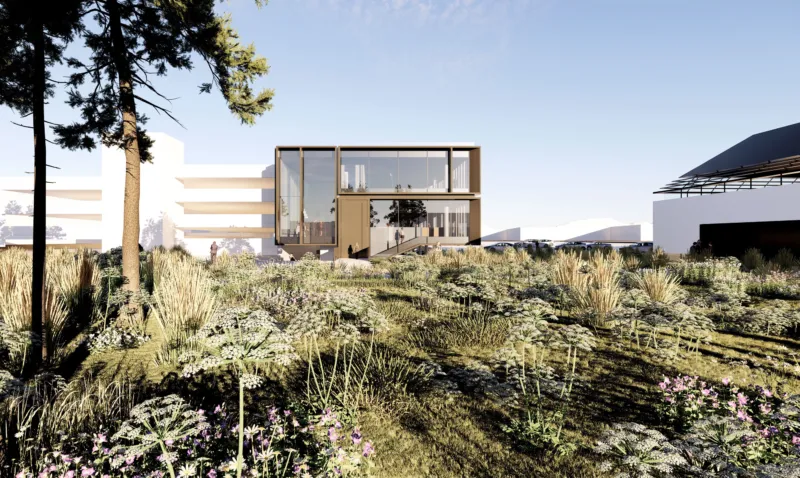 Two-story glass-front building with wooden frame in a sunlit campus, surrounded by native grasses and flowers; a few people near the entrance.
