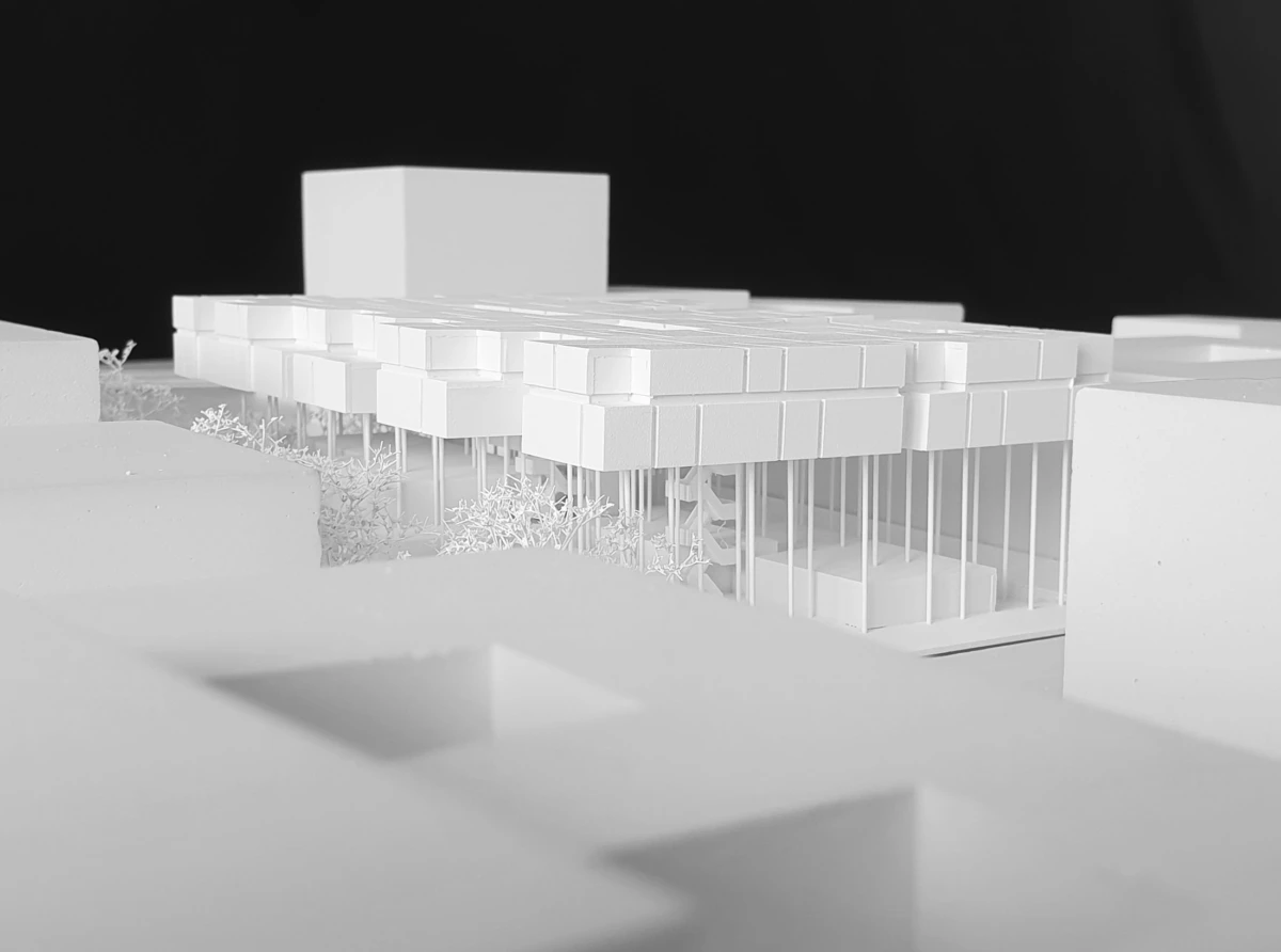 White architectural model of a modern building with cantilevered slabs on slender columns, set on a flat base.