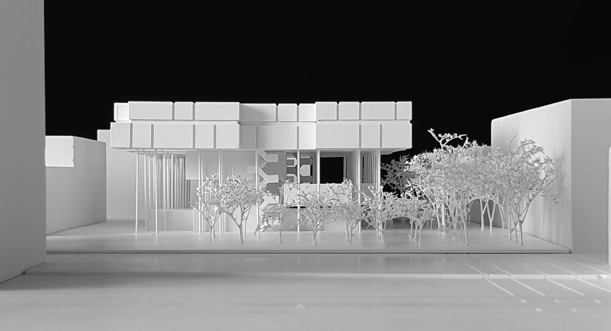 Architectural scale model of a modern building with a flat roof and slender columns, with a row of trees in front on a white base.