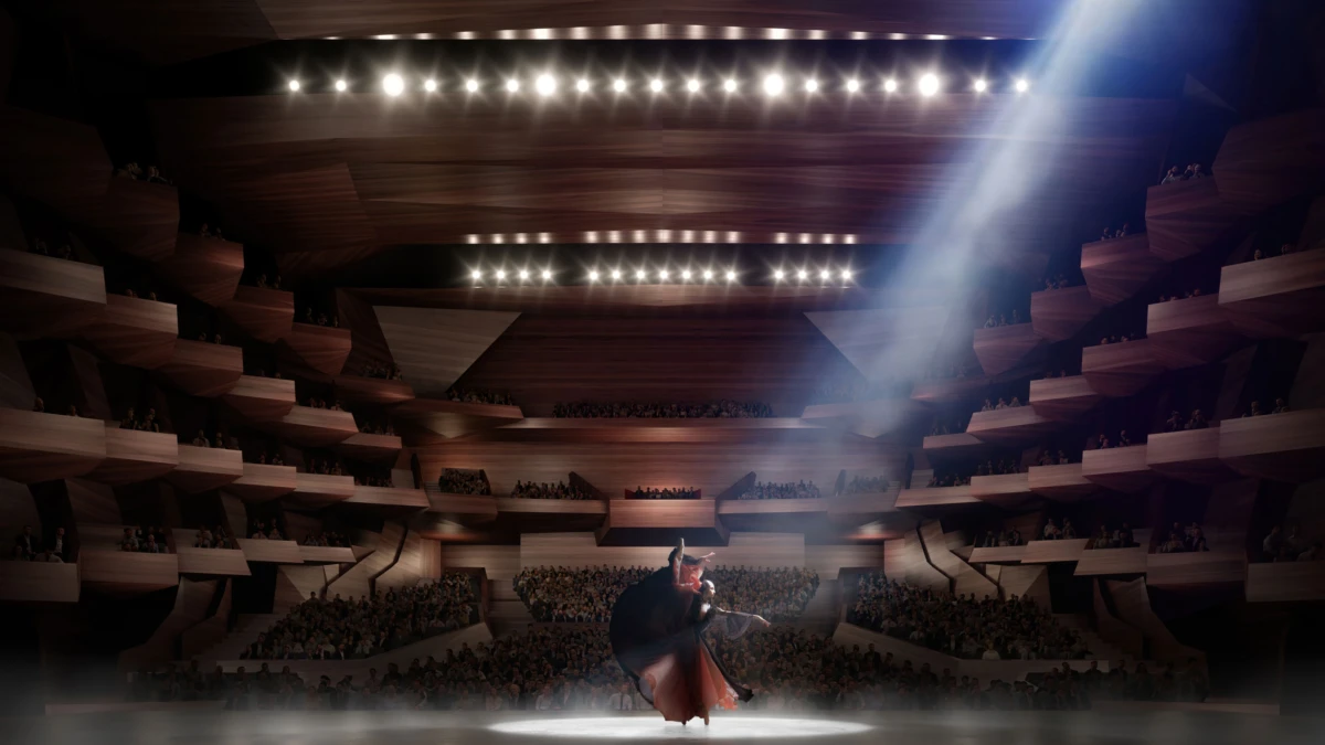 Dancer in red cape performing center stage under a spotlight in a wood-paneled, multi-tiered concert hall with an audience